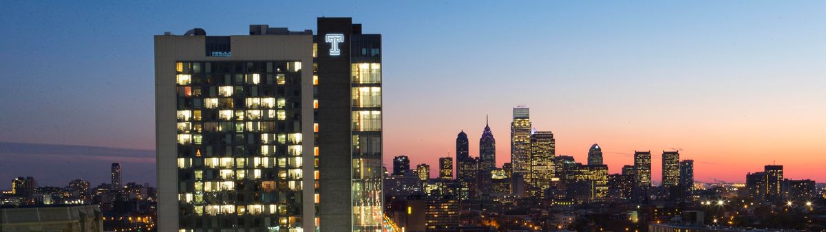 a photograph of a building with the Temple 'T' with the Philadelphia skyline in the background